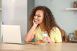© Pixel-Shot - Young African-American woman with laptop drinking milk in kitchen