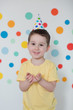 © aprilante - Toddler boy in the birthday hat on a background of wall with colorful circles