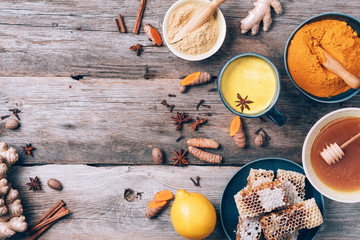 Wall Mural - Ingredients for turmeric latte. Turmeric powder, curcuma root, cinnamon, ginger over wooden background. Copy space. Antiviral beverage. Spices for ayurvedic treatment. Alternative medicine concept.