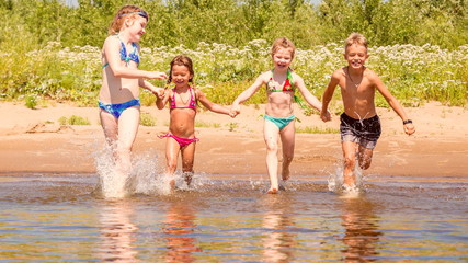 Wall Mural - group of beautiful children runs in a wig and splashes water on a summer hot sunny day