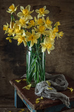 Bouquet Of Fresh Yellow Spring Flowers Of Daffodils In Different Vases On An Old Wooden Vintage Background. Still Life.