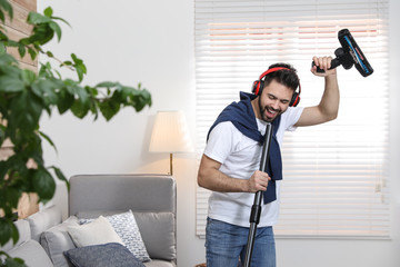 Wall Mural - Young man having fun while vacuuming at home