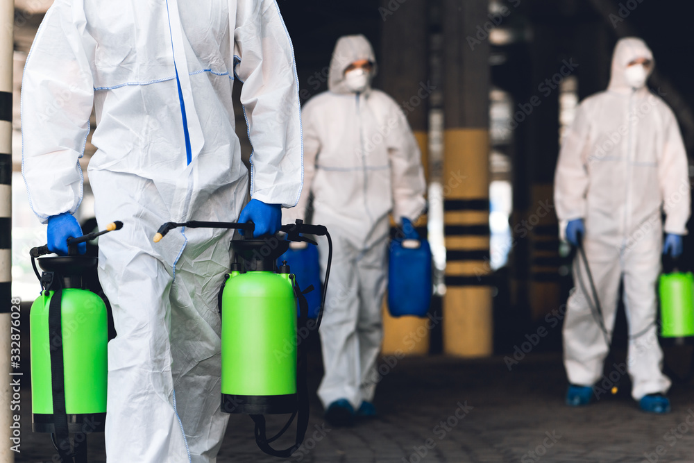 Men in virus protective suits carrying spray bottles with chemicals - obrazy, fototapety, plakaty 
