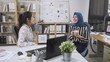 © PRPicturesProduction - Group of young multi ethnic colleague people sales sitting at desktop computer having fun and drinking coffee in cups for tea break. two asian women workers chatting relax laughing gossip in company.