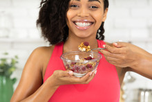 Black girl eating granola with yogurt in bowl