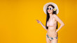 © anon - Beautiful,Sexy asian girl standing on yellow background in a pink bikini and smiling.Summer vocation happy trip concept.