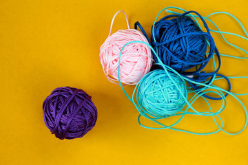 Top view of colorful nylon thread balls on yellow background. Concept of individuality.