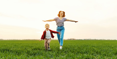 Wall Mural - happy woman with kid running in field.