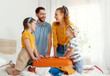 © JenkoAtaman - Excited family packing baggage on bed anticipating trip.