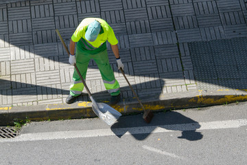 Street sweeper with broom and shovel working on city. Public cleaning concept