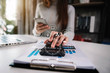 © NINENII - Female businessman calculates financials with graph paper on the laptop computer, cell phone on the cost of home office.