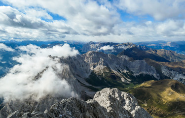 Sharp and rocky mountains range at Austrian-Italian border. There s a path mark on a stone. Serenity and peace. Clouds breaching high mountains. Lots of loose rocks, possibility of landslide