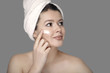 © romandatso - woman in towel smears cream on her face ￼