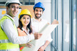 © Kawee - Young engineer group of home building member discuss for project planning. Asian man hold blueprint drawing while all team members look project area. People brainstorm teamwork for idea of structure.