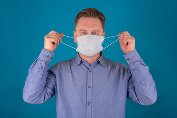 Close-up portrait of an adult man wearing a medical mask to protect against viruses. Corona virus covid-19. Isolate on a blue background. Concept of medicine and healthcare.