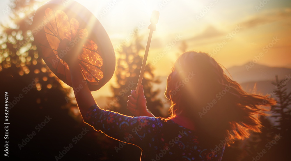 beautiful shamanic girl playing on shaman frame drum in the nature. - obrazy, fototapety, plakaty 