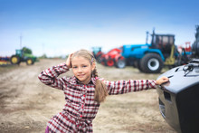 Cute Girl Near The Modern Tractor In The Field.