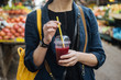 © Pietro Karras/Stocksy - Woman with shake in cup on street near shops