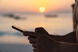 © Kike Arnaiz/Stocksy - Hands holding a cellphone with the sunset background