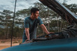 © Kike Arnaiz/Stocksy - up of a man checking the engine of the 4x4 vehicle. On a dirt ro