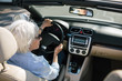 © Rob and Julia Campbell/Stocksy - Relaxed older woman driving convertable car.
