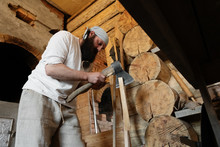 Man Splitting Logs In Rural House