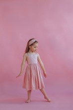 Lovely Little Girl In Pink Dress Dancing By Pink Background