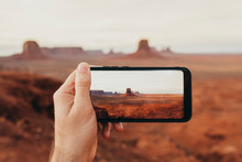 Hand Holding A Phone While Taking A Photo Of Typical Utah Landscape