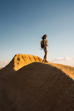 Young Woman Doing Hiking With A Backpack On Top Of A Big Rock, During Sunrise