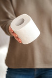 Fototapeta Morze - The girl shares toilet paper and holds out the roll forward.People are stocking up toilet paper for home quarantine from crownavirus. preparation for quarantine and economic crisis due to coronavirus.