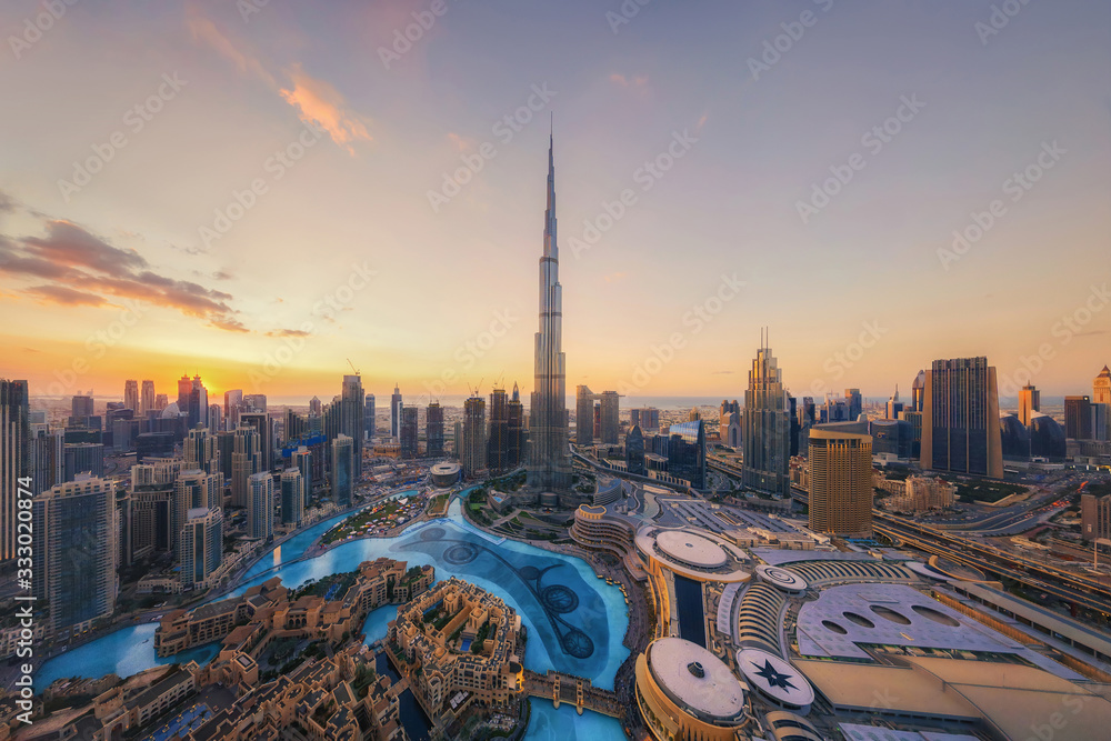Aerial view of Burj Khalifa in Dubai Downtown skyline and fountain, United Arab Emirates or UAE. Financial district and business area in smart urban city. Skyscraper and high-rise buildings at sunset. - obrazy, fototapety, plakaty 