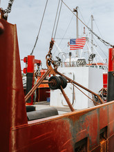 An American Flag Aboard A Fishing Boat Parked In A Harbor Along The North Atlantic Seaboard