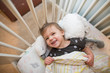© Cavan Images - High angle of cute toddler girl smiling in her bed