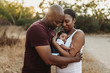 © Cavan Images - Close up happy mother and father cuddling infant girl backlit field