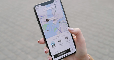 new york - mar 20, 2020: close up of smartphone in female hands. woman using phone and ordering car 