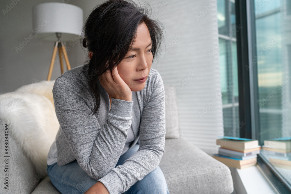 Sad Asian mature woman lonely at home self isolation quarantine for COVID-19 Coronavirus social distancing prevention. Mental health, anxiety depressed thinking senior chinese lady. - obrazy, fototapety, plakaty 