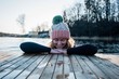 © Cavan Images - Woman smiling leaning on a jetty whilst in the sea cold water swimming