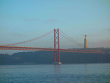 Fototapeta Sypialnia - Lisbon, Portugal-23 December 219: skyline, red bridge on 25 April crossing the river Tejo on a cloudy day at dusk in the background Christ the King.