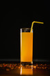 Orange juice with yellow straw isolated on black background