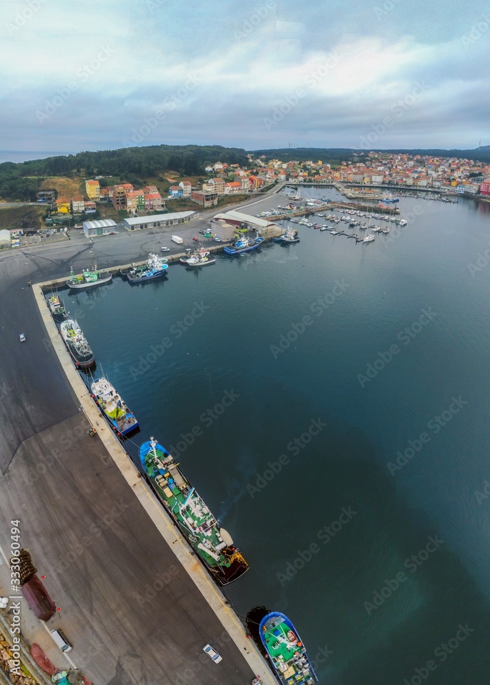 Vertical shot of boats on the water under a cloudy sky in Galicia, Spain - obrazy, fototapety, plakaty 