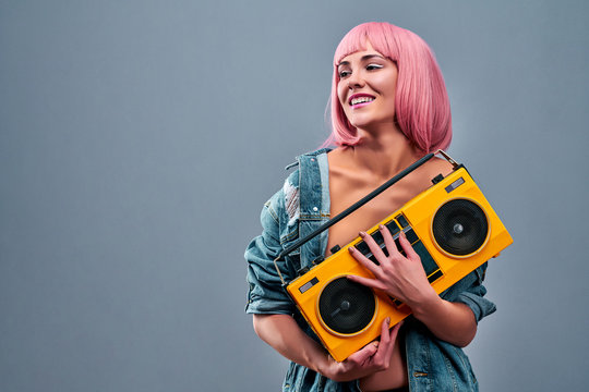 Hi, baby. Portrait of peaceful cool girl holding boom box with cassette tape going to make party isolated on grey background.