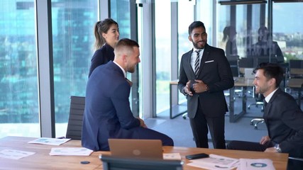 Wall Mural - Emotional male and female partners laughing during working day in corporate company, excited diversity group of employees enjoying brainstorming meeting in office interior