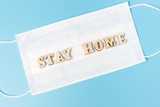 Fototapeta  - Stay home inscription on white mask, blue background top view