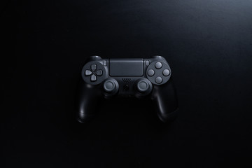 A black game controller isolated on black background.