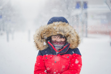 Wall Mural - Cute Asian child wearing winter clothes playing on snow in the park