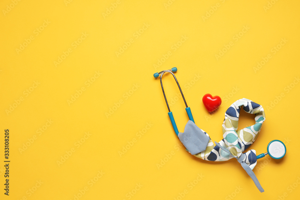 Stethoscope with cover and heart on color background