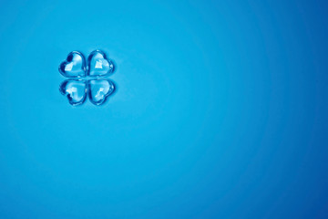 Imitation of a Lucky four leaf clover with four glass hearts on a blue background for St. Patricks Day. Space for text, digital texture design concept. Creative Tinting. Trend color classic blue.