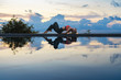 © mizuno555 - Young woman with long hair doing yoga early morning outdoor by the pool with sea view