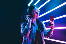 Sillhoutte Of Hip-hop Girl With Headphones At The Neon Light. Fashion Portrait Of Modern Young Woman Making Selfie.