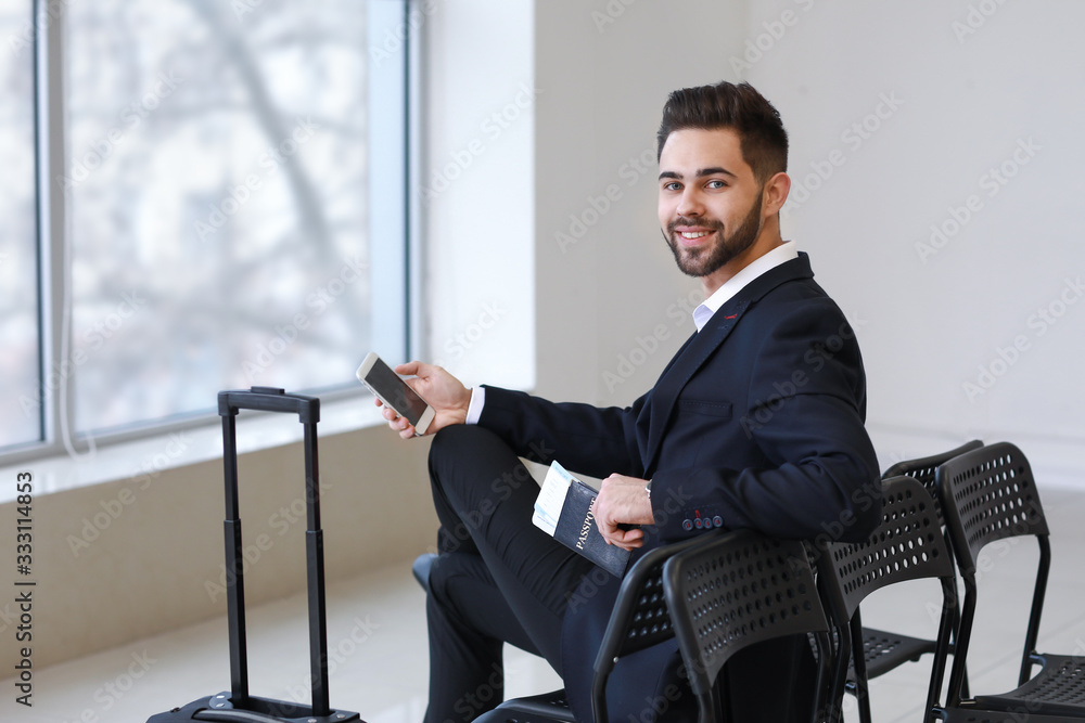 Young businessman with documents and mobile phone at the airport